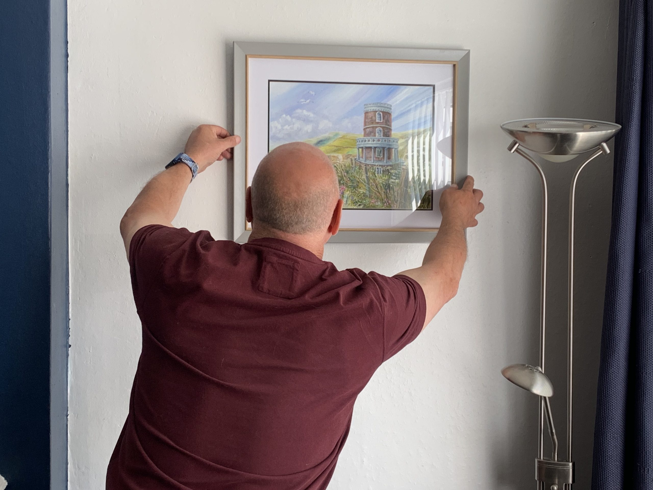 Mr Morgan hanging his newly commissioned painting 'Clavell Tower - the original' painted by Shaun Forward